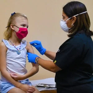 Masked child getting medical shot from nurse for yearly checkup